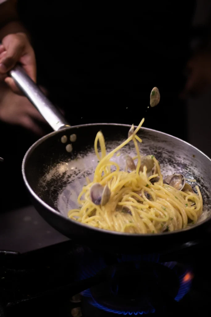Koch bereitet Spaghetti alle vongole in der Pfanne zu, Küche des Cantinone Storico, Venedig