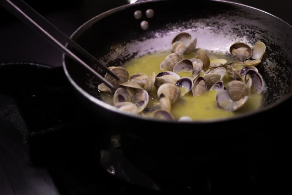 In der Pfanne sautierte Venusmuscheln, Zubereitung eines Fischgerichts im Cantinone Storico Venedig